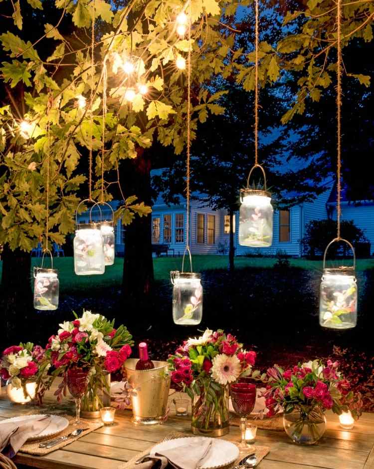 Weckgläser mit Lichterketten und Blumen für romantische Partydeko im Garten