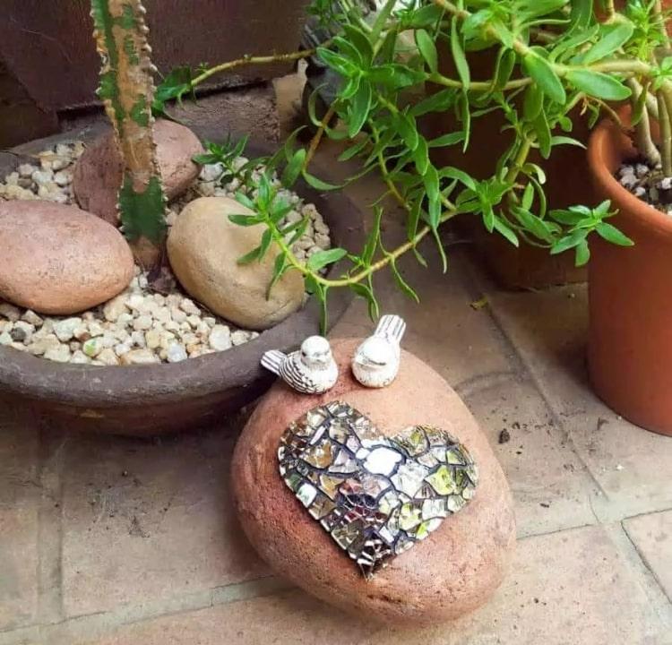 Herz aus Mosaiksteinchen und Vögel auf einem großen Stein als Gartendeko