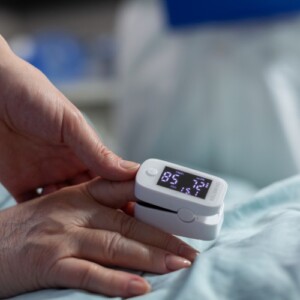 arzt kontrolliert niedrige hämoglobinwerte von älteren patientin mit oximeter