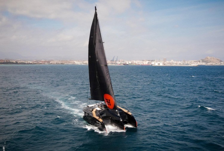 designer dreirumpfboot mit schwarzen segeln im wasser