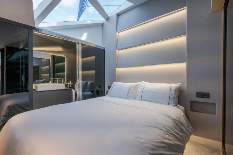 ein großes doppelbett und kleiderschrank mit glastüren im schlafzimmer mit glasdecke