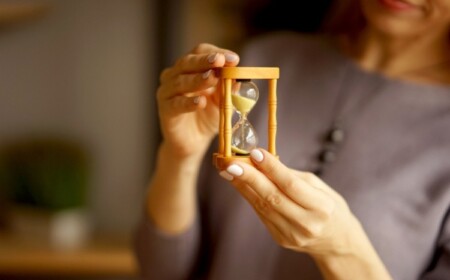 frau hält eine sanduhr als symbol für lebenserwartung