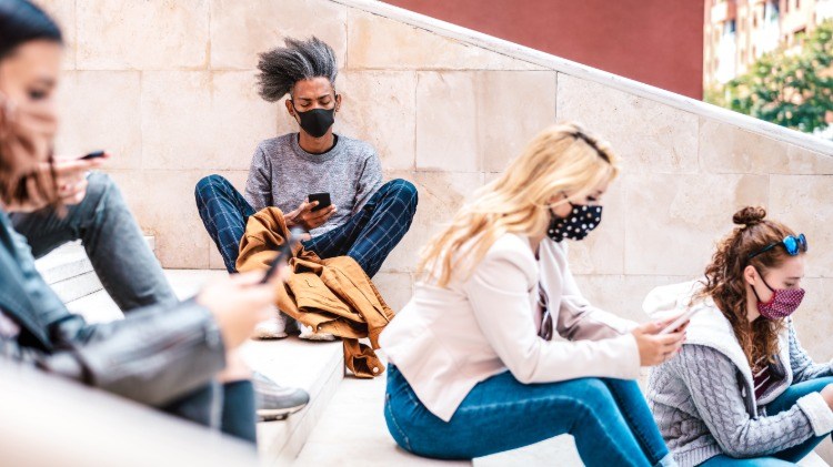 junge menschen mit schutzmasken sitzen an treppen während der pandemie covid 19