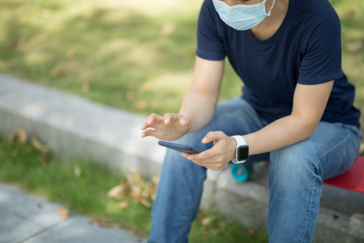 junge mit schutzmaske nutzt smartwatch und fitnesstracker als gesundheitsverfolger bei covid 19
