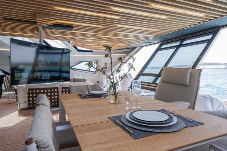 wohnbereich mit riesigem fernseher und esstisch in trimaran yacht hanstaiger x1