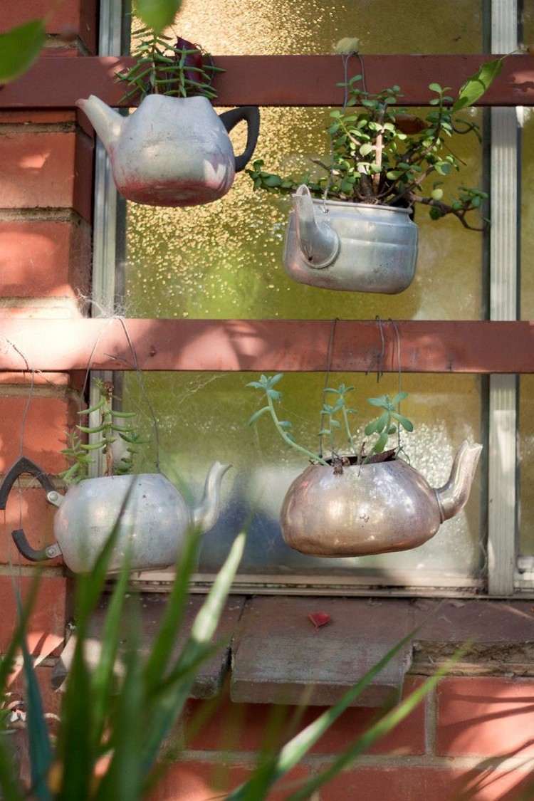 Gartendeko Ideen mit hängenden Teekannen mit Pflanzen