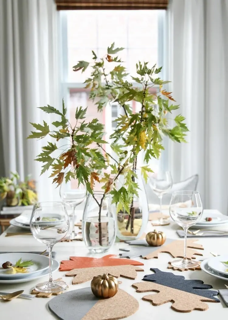 Frische Herbstblätter an Zweigen für eine puristische Tischdekoration im Glas