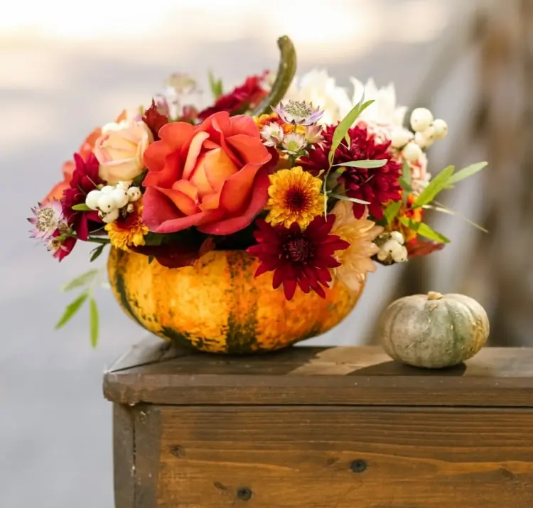 Gesteck im Kürbis als Herbstdeko für den Tisch basteln in warmen Farben