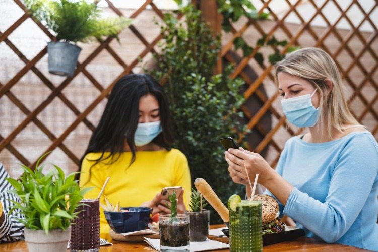 frauen tragen masken vor der mahlzeit während der pandemie