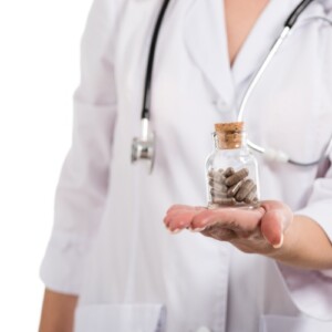 medizinerin hält präbiotika und probiotika in form von pillen in einer flasche