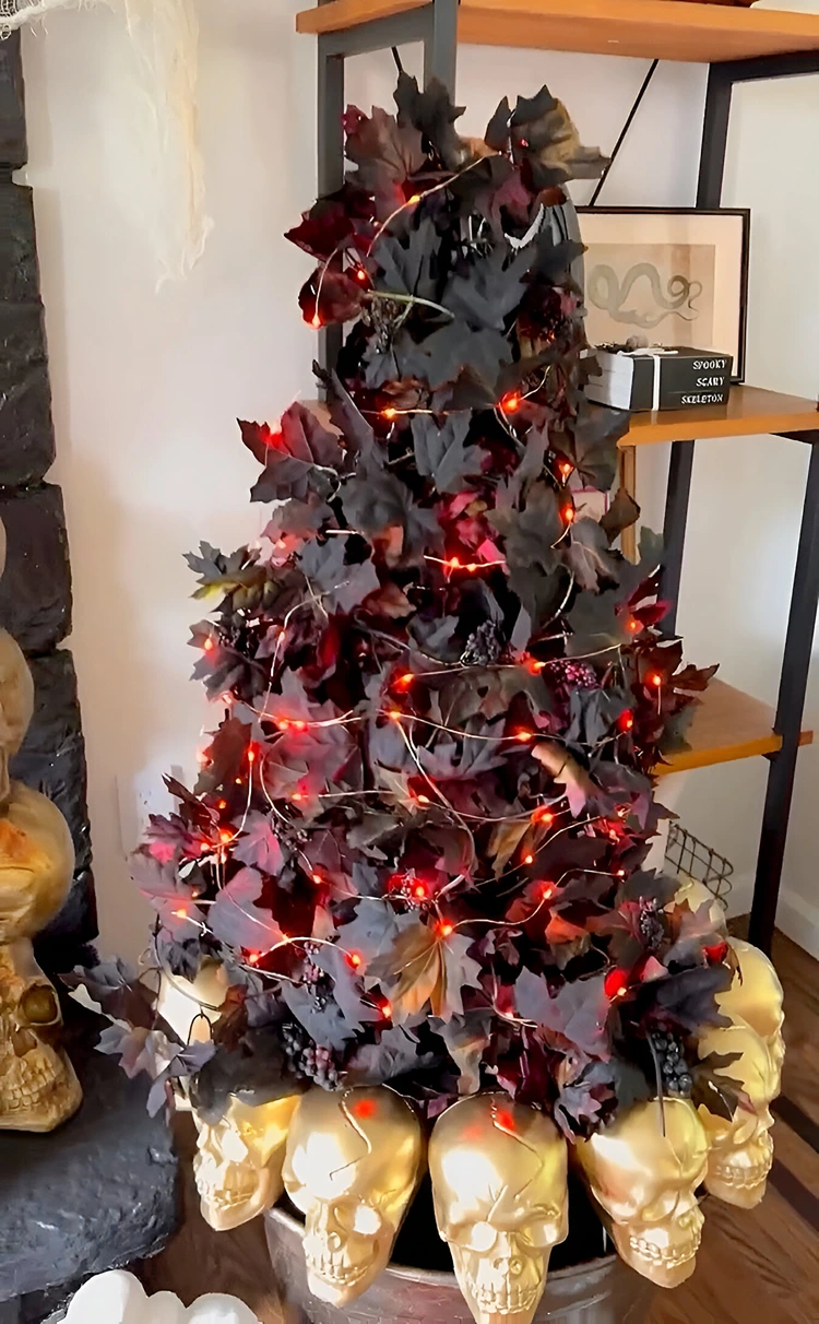 Schöne Halloweendeko im Kübel mit Totenköpfen, Blattgirlande und roter Lichterkette