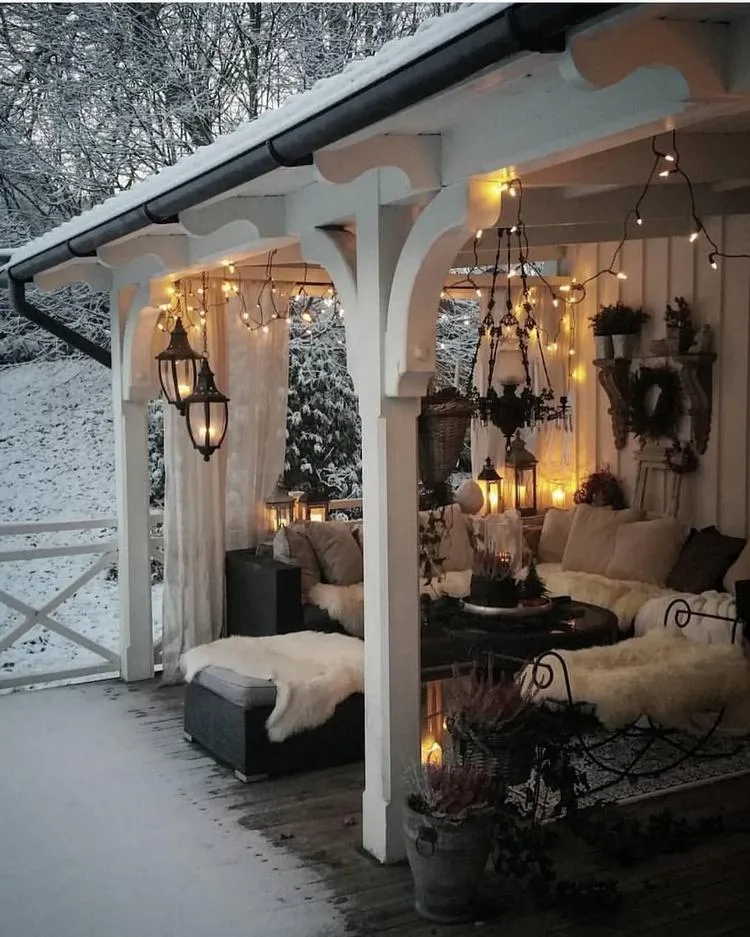 Gemütliche Terrasse im Winter mit Lichterketten und weiche Textilien dekoriert