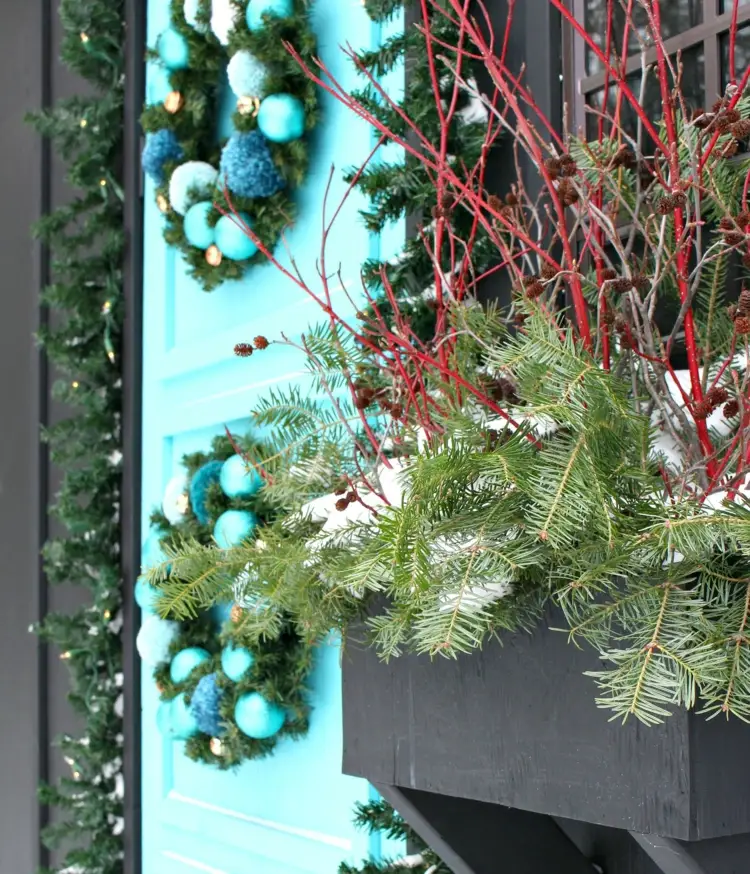 Grüne Tannenzweige und rote Zweige als Akzente im Weihnachtsarrangement im Kasten