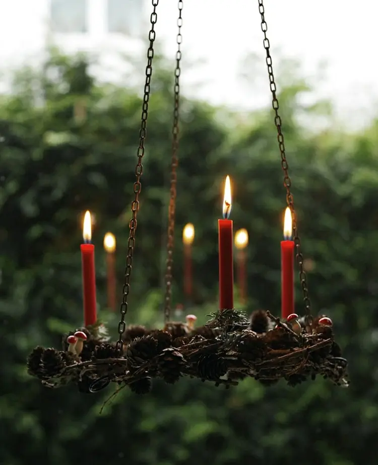 Hängender Adventskranz aus Tannenzapfen und Zweigen mit Tafelkerzen