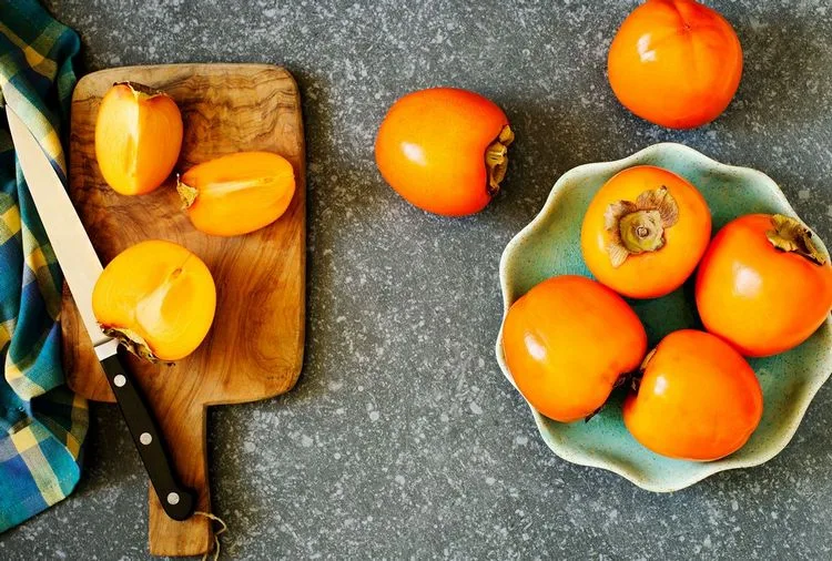 Kaki essen mit Schale in Spalten aufschneiden