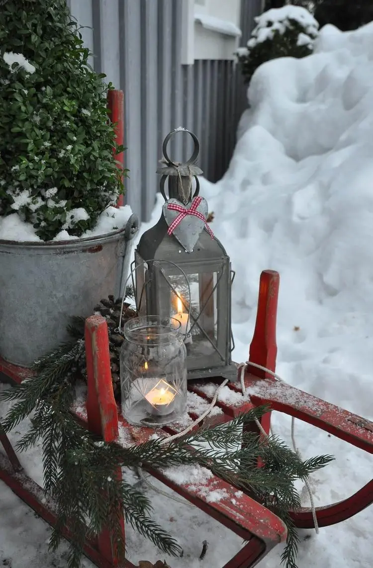 Winterdeko für Garten alter Schlitten mit Laternen und Buchsbaum im Kübel dekorieren