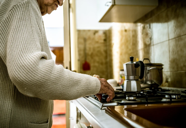 ältere person mit demenzerkrankunge bei kaffeezubereitung auf dem herd