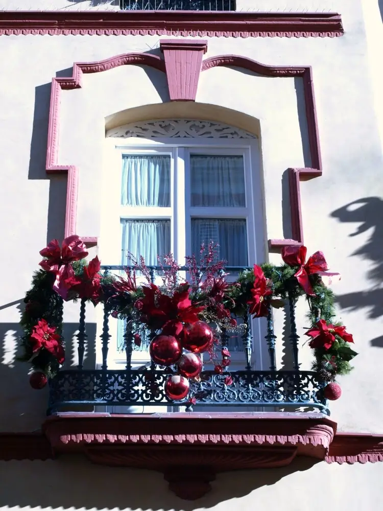 balkongeländer weihnachtlich schmücken mit tannengirlande mit roten dekorationen