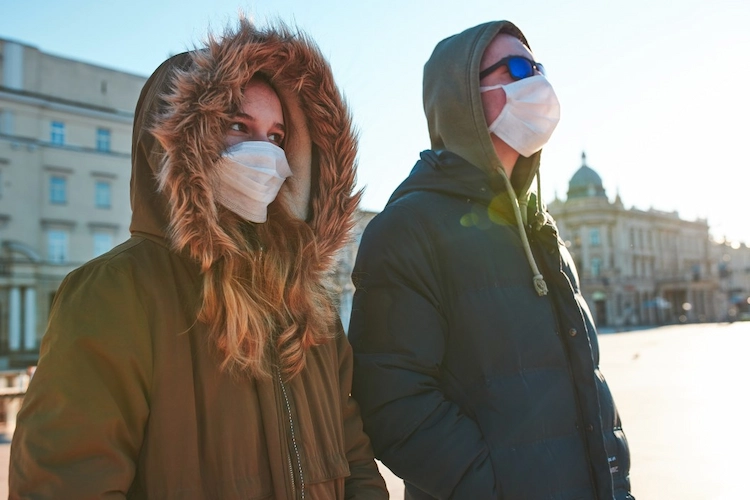 junge menschen mit schutzmasken auf der straße während covid 19 pandemie