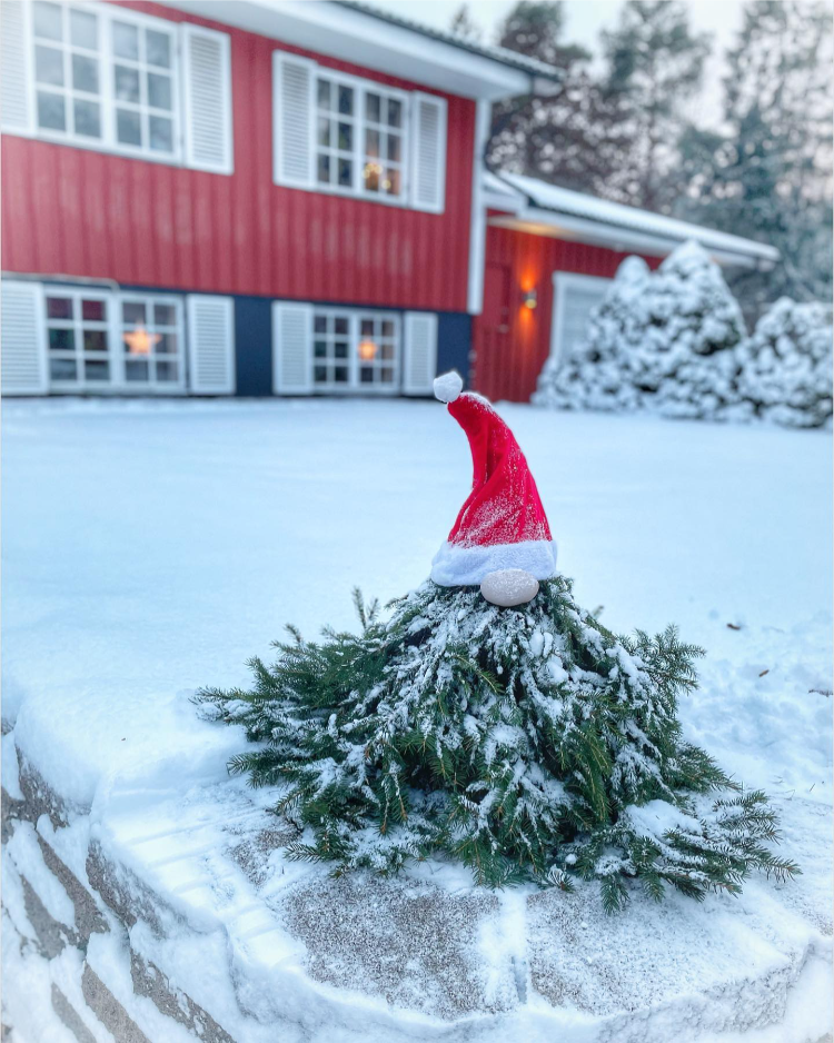 diy wichtel aus tannenzweigen und weihnachtsmütze draußen im garten mit schnee