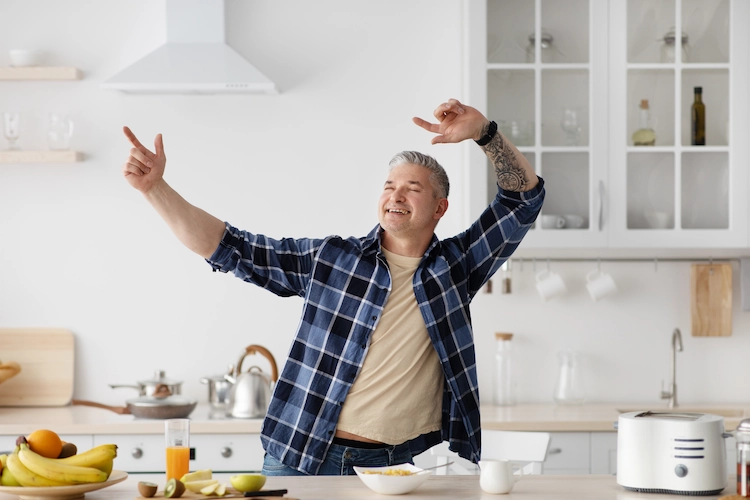 glücklicher älterer mann tanzt in der küche