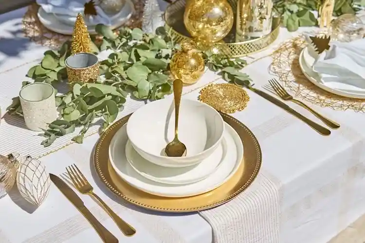 goldfarbenes Besteck und goldene Untersetzer im Kontrast zu den weißenn Tellern