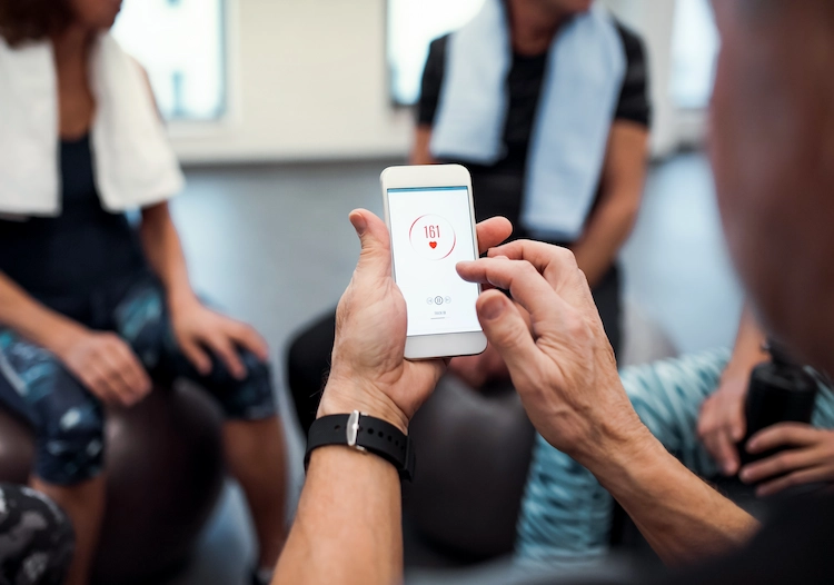 senioren im fitnessraum messen ihre herzfrequenz auf einem handy