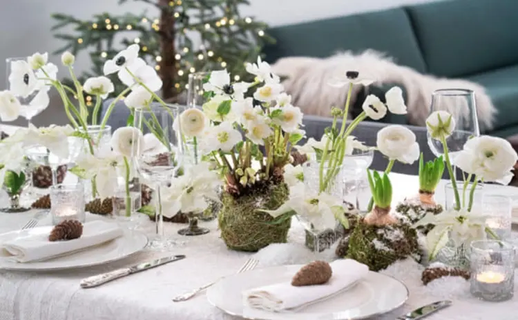 weihnachtliche tischdeko mit christrosen, ranunkeln und weißen weihnachtssternen