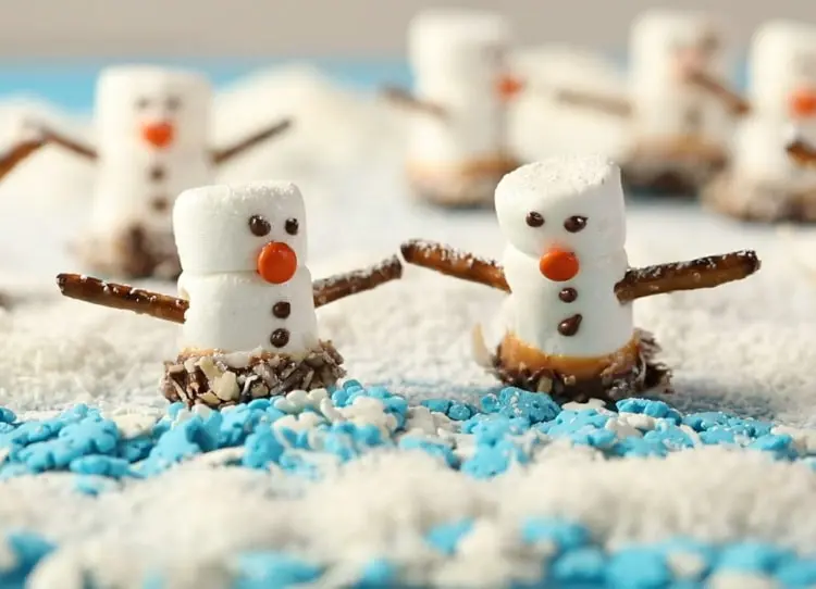 Mini-Schneemänner aus Marshmallows mit Schokolade und Salzstangen dekoriert