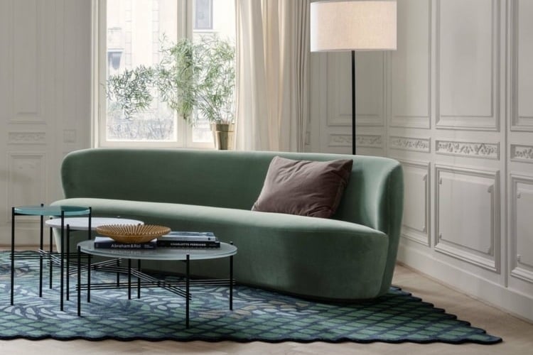 Runde Couch im Wohnzimmer in dezentem Grün mit abstrakt gemustertem Teppich