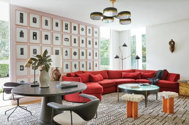 Runde Couch in Rot im Wohnzimmer mit Kontrast-Formen durch eine Bilder-Wand