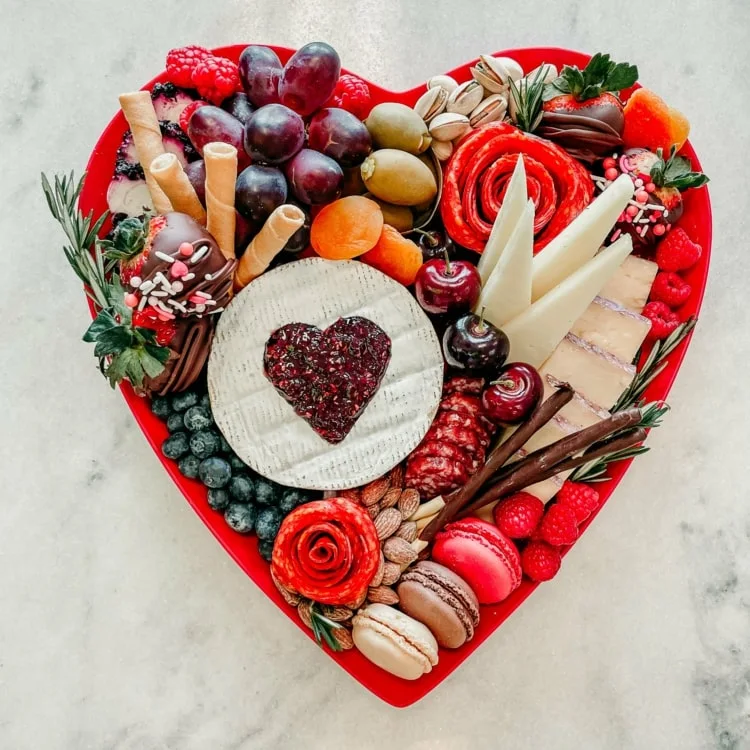 Herzförmige Charcuterie Boards zum Tag der Verliebten mit Käse, Weintrauben, Blaubeeren, Salami-Rosen