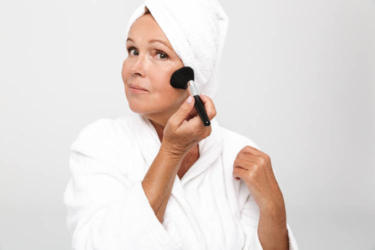 Ältere frau, die sich rouge auf die wangen aufträgt