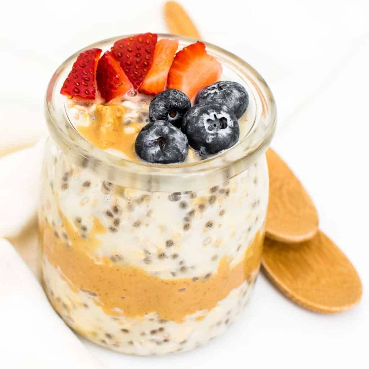 gesundes frühstück mit overnight oats zum abnehmen und beeren im glas mit erdnussbutter kombiniert