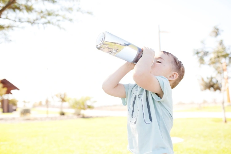 Junge trinkt Leitungswasser in Flasche warum viel im Frühling trinken
