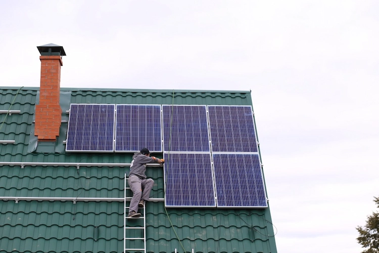 installateur von solarpaneelen arbeitet auf einem schrägen dach mit leiter
