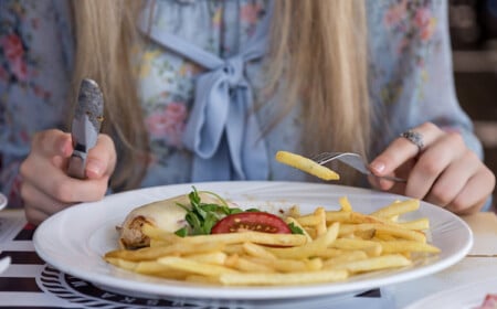 junge frau isst zum mittag eine portion pommes mit 300 kalorien