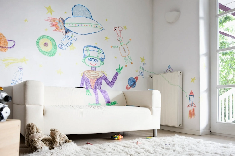 kinderzeichnungen mit malkreide auf wänden und polstermöbeln im wohnzimmer