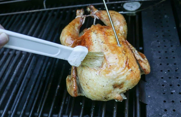 ein ganzes hähnchen grillen und mit gebundenen keulen nach der würzung mit butter beschmieren