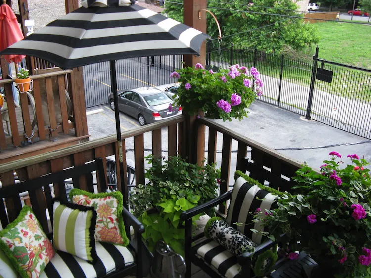 gemütlich eingerichteter balkongarten mit gestreifter sonnenschirm