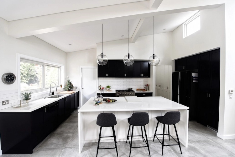 in schwarz und weiss gestalteter küchenraum mit kücheninsel und stühlen