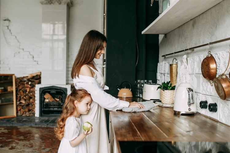 young woman and her daughter clean the kitchen countertop in rustic style