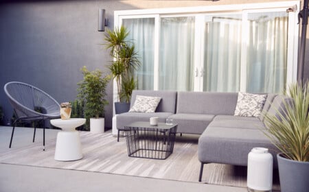 moderner außenbereich mit bequemen gartensesseln und sofa in grau mit weißer deko kombiniert