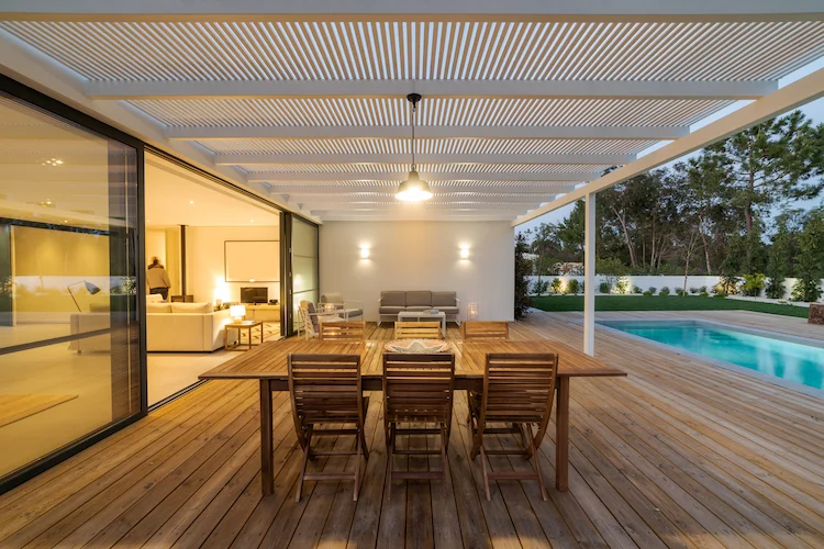 modernes haus mit pool und terrasse im außenbereich mit holzdielen und großem esstisch