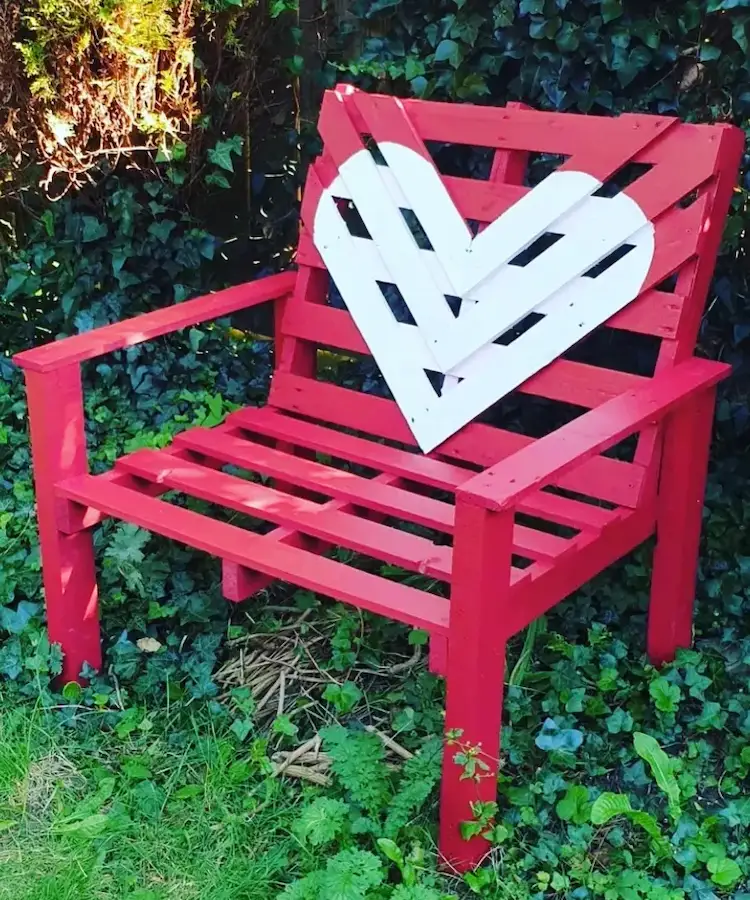 roter stuhl aus palettenholz bemalt mit weißem herz in der mitte als sitzgelegenheit im gartenbereich