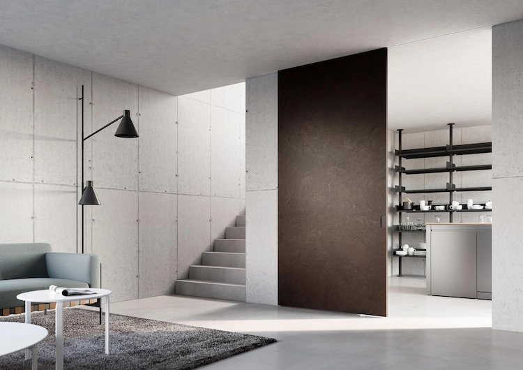 wohnraum mit eingebauter küche in industriellem stil durch große tür in rostigem look getrennt