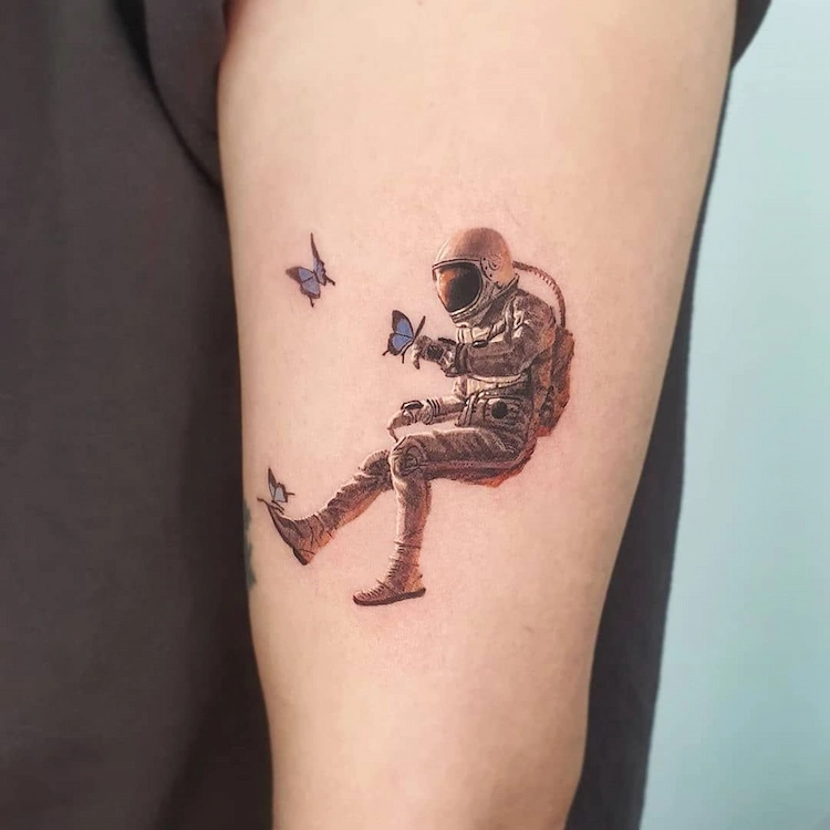 kleine tätowierungen auf der arm nach mikrorealismus tattoo trends 2022 mit austronaut und schmetterlingen