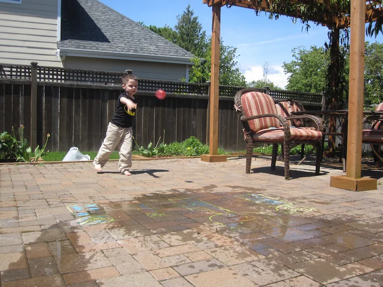 kleinkind wirft einen mit wasser gefüllten ballon auf spielfiguren aus dem videospiel angry bird im hinterhof