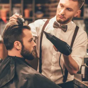 modebewusster mann beim friseur lässt sich die haare und den bart stylisch schneiden