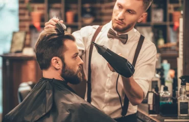 modebewusster mann beim friseur lässt sich die haare und den bart stylisch schneiden